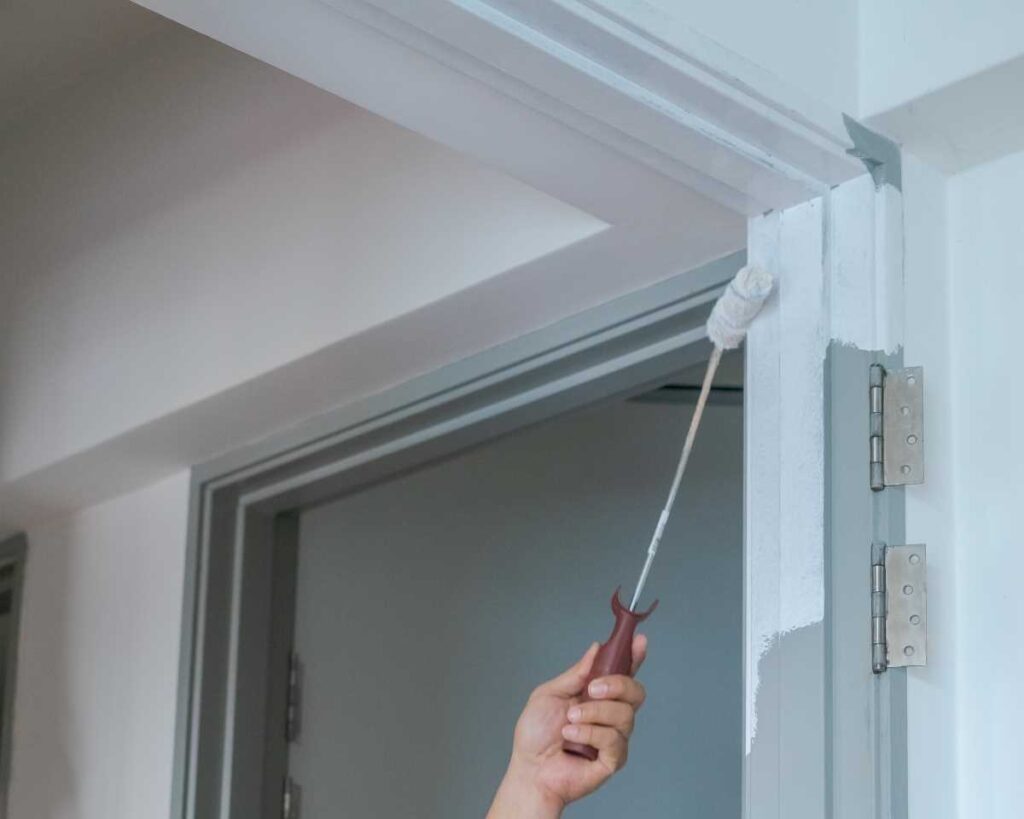 Person painting the inside of a door frame | Featured image for the Home Repair Services Page for Tribella Group.